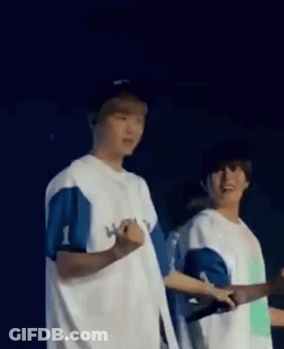 A Couple Of Men Standing Next To Each Other On A Stage . GIF