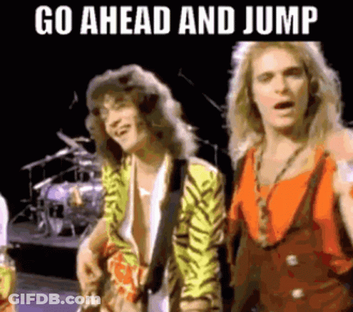 A Couple Of Men Standing Next To Each Other On A Stage With The Words `` Go Ahead And Jump '' Written Above Them . GIF