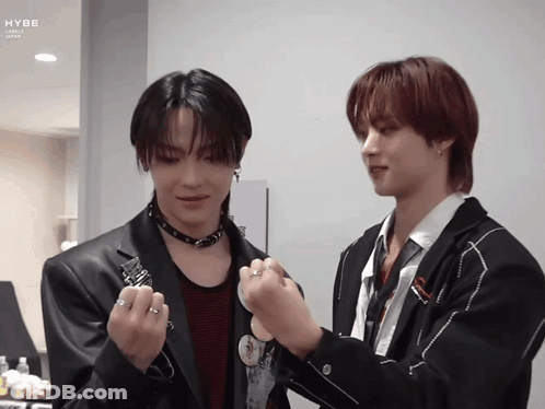 A Couple Of Men Standing Next To Each Other With The Word Hybe On The Bottom Left GIF