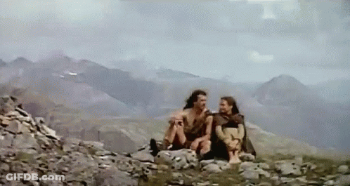 A Couple Of People Are Sitting On Top Of A Rocky Mountain . GIF