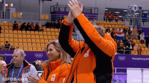 A Couple Of People Giving Each Other A High Five In Front Of A Pyeongchang Sign GIF
