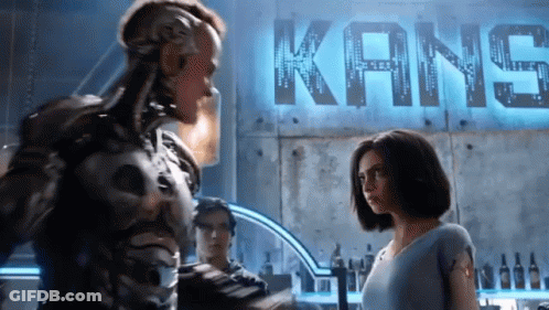 A Couple Of People Standing In Front Of A Kane Sign GIF