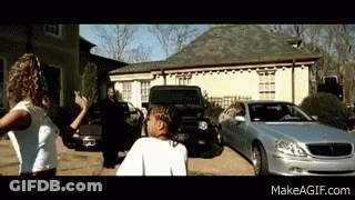 A Couple Of People Standing In Front Of A Silver Car And A House GIF