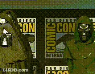 A Couple Of People Standing In Front Of Comic Con Posters GIF