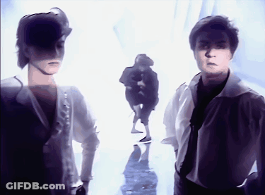 A Couple Of People Standing Next To Each Other In A White Room GIF