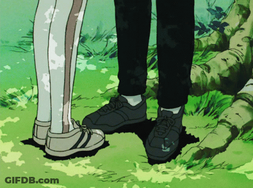 A Couple Of People Standing Next To Each Other With Their Feet In The Grass GIF