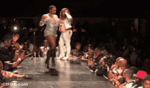 A Couple Of People Walking Down A Runway In Front Of A Crowd Of People GIF