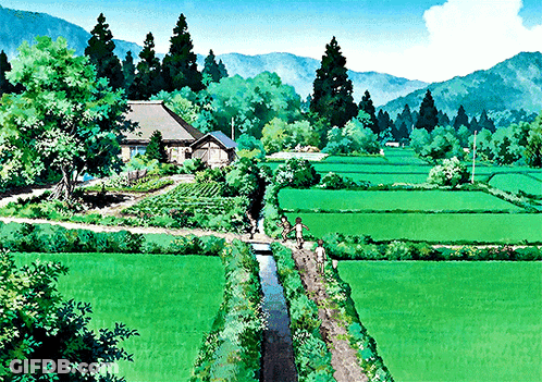A Couple Of People Walking Through A Lush Green Field With Mountains In The Background GIF