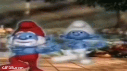 A Couple Of Smurfs Are Dancing On A Wooden Table . GIF