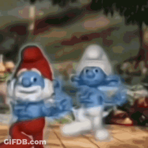 A Couple Of Smurfs Are Standing Next To Each Other On A Table GIF
