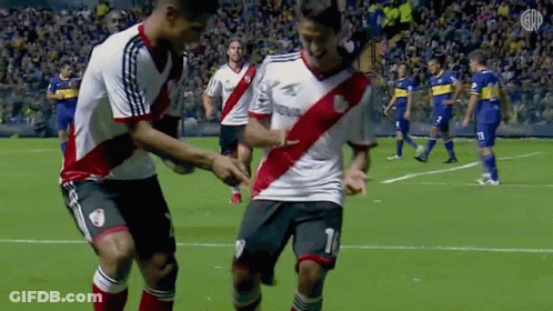 A Couple Of Soccer Players Are Dancing On The Field . GIF