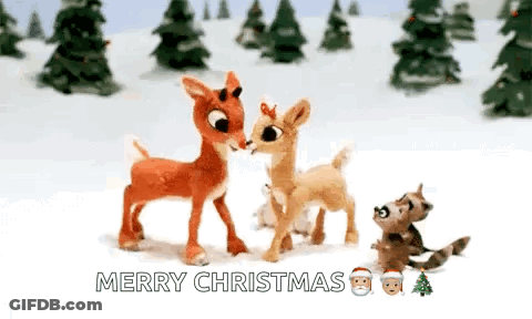 A Couple Of Stuffed Deer Standing Next To Each Other In The Snow With Trees In The Background . GIF