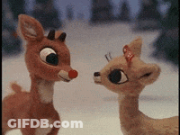 A Couple Of Stuffed Reindeer Standing Next To Each Other In The Snow GIF