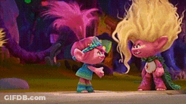 A Couple Of Trolls Standing Next To Each Other On A Sidewalk In A Forest . GIF