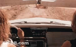 A Couple Of Women Are Driving A Car Down A Dirt Road . GIF