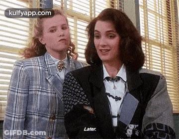 A Couple Of Women Are Standing Next To Each Other In Front Of A Window . GIF