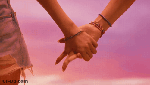A Couple Of Women Holding Hands With Bracelets On Their Wrists GIF
