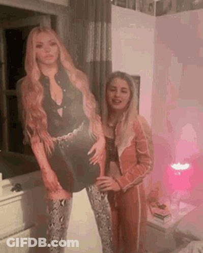 A Couple Of Women Standing Next To Each Other In A Room . GIF