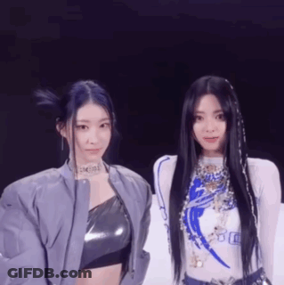 A Couple Of Women Standing Next To Each Other On A Stage . GIF