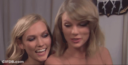 A Couple Of Women Standing Next To Each Other Smiling And Laughing . GIF