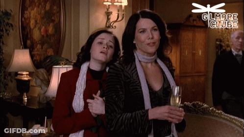 A Couple Of Women Standing Next To Each Other With A Dragonfly Above Them That Says Glmore Clube GIF
