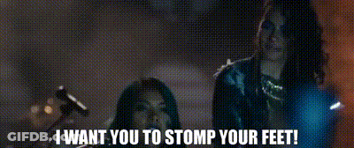 A Couple Of Women Standing Next To Each Other With The Words `` I Want You To Stomp Your Feet '' Written On The Screen . GIF