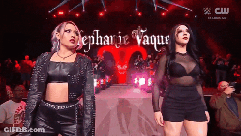 A Couple Of Women Standing On A Stage With The Name Stephanie Vaque Written On It GIF
