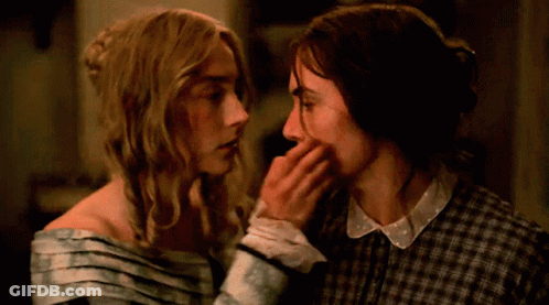 A Couple Of Women Touching Each Other 'S Faces In A Dark Room GIF