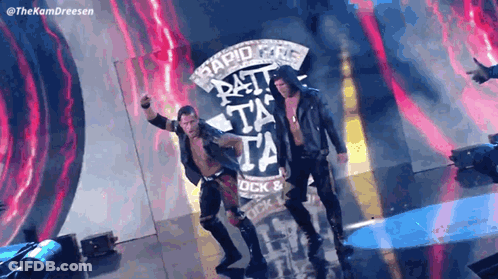 A Couple Of Wrestlers Are Standing In Front Of A Sign That Says Rapid Fire GIF