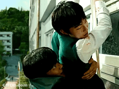 A Couple Of Young Men Are Hugging Each Other In Front Of A Window . GIF