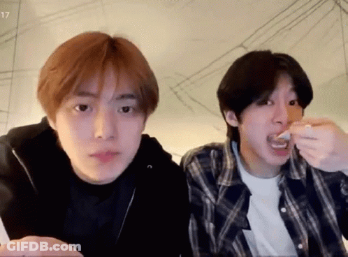 A Couple Of Young Men Are Sitting Next To Each Other And Eating Food . GIF