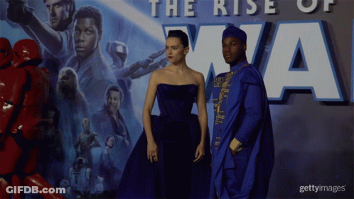 A Couple Standing In Front Of A Poster That Says The Rise Of Xna GIF