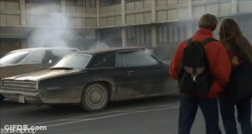 A Couple Standing Next To A Car That Has Smoke Coming Out Of It And The Words Zona-Hiphop On The Bottom GIF
