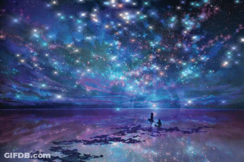 A Couple Standing On A Beach Looking Up At The Stars GIF