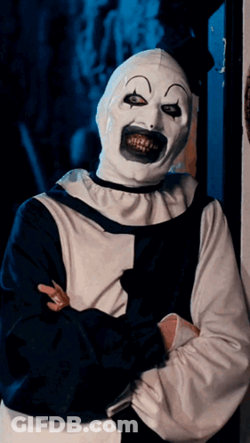 A Creepy Clown With A Huge Smile On His Face Is Standing With His Arms Crossed GIF