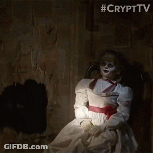 A Creepy Doll In A White Dress Is Sitting In A Chair GIF