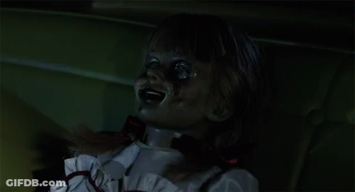 A Creepy Doll With Blood On Her Face And A Red Bow Around Her Neck GIF