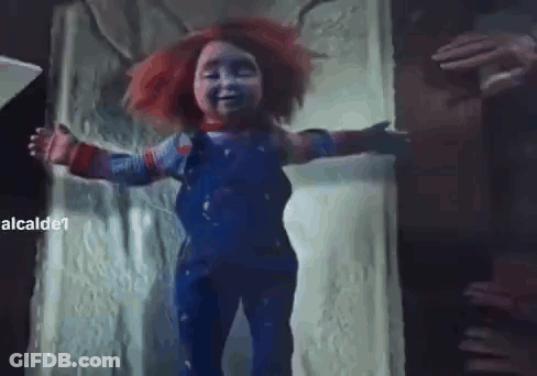 A Creepy Doll With Red Hair And Blue Overalls Is Standing In A Doorway With Its Arms Outstretched . GIF