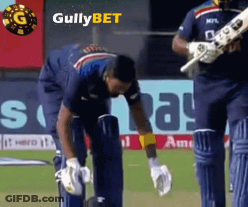A Cricket Player Is Kneeling Down On The Field With A Gullybet Logo In The Background GIF