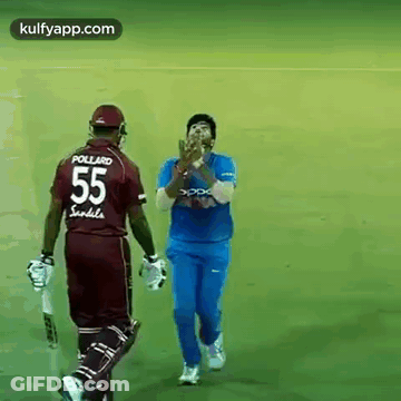 A Cricket Player Wearing A Jersey With The Number 55 On It Is Walking Towards Another Player . GIF