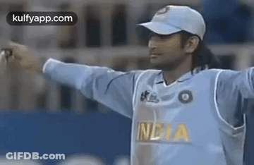 A Cricket Player Wearing A White Hat And A Blue Jersey Is Standing On A Field . GIF