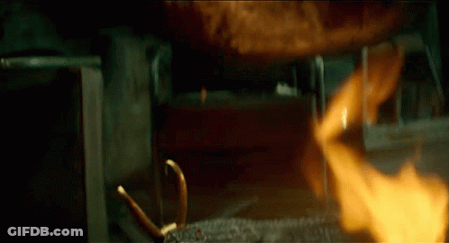 A Crocodile With Horns Is Laying In Front Of A Fire GIF