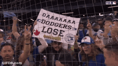 A Crowd Of Blue Jays Fans Holding A Sign That Says Dodgers Lose GIF
