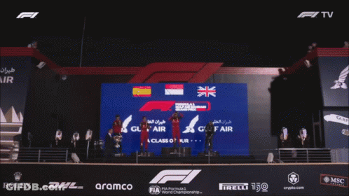 A Crowd Of People Applauding In Front Of A Fence That Says Class Of Ducrown GIF