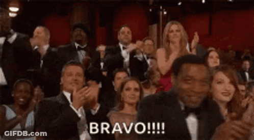 A Crowd Of People Are Applauding At An Awards Ceremony And The Word Bravo Is Written On The Screen . GIF