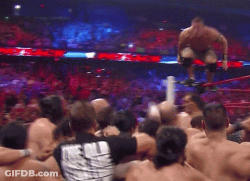 A Crowd Of People Are Gathered Around A Wrestling Ring With A Man Kneeling On A Rope GIF