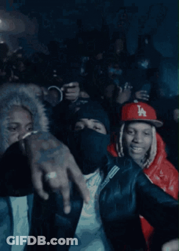 A Crowd Of People Are Gathered In A Dark Room And One Of Them Is Wearing A Ny Hat GIF