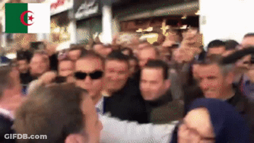 A Crowd Of People Are Gathered In Front Of A Flag That Says Algeria On It GIF