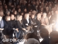 A Crowd Of People Are Sitting In A Stadium At A Fashion Show . GIF