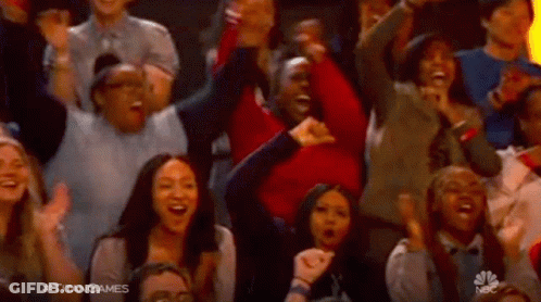 A Crowd Of People Are Sitting In A Stadium Cheering And Laughing . GIF